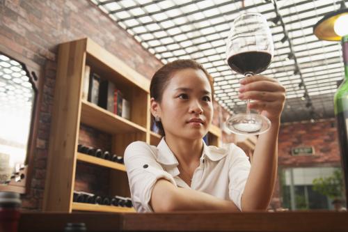 Mujer mirando una copa de vino tinto