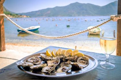 Ostras en un plato blanco con limón y una copa de vino