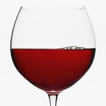 Copa de globo de vino tinto sobre fondo blanco.